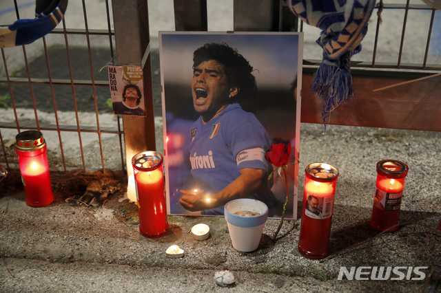 [나폴리=AP/뉴시스]25일(현지시간) 이탈리아 나폴리에 있는 SSC 나폴리의 홈구장인 산 파올로 경기장 밖에 디에고 마라도나의 사진과 그를 추모하는 촛불이 놓여 있다. 1986년 아르헨티나를 월드컵 우승으로 이끈 아르헨티나 축구 영웅 디에고 마라도나가 25일 아르헨티나 부에노스아이레스 자택에서 심장마비로 타계했다. 향년 60세. 2020.11.26. 