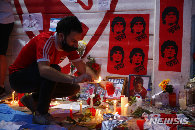  [부에노스아이레스=AP/뉴시스]25일(현지시간) 아르헨티나 부에노스아이레스의 아르헨티노스 주니어스 경기장 밖에서 한 축구 팬이 디에고 마라도나의 포스터 앞에 촛불을 밝히며 그를 추모하고 있다. 1986년 아르헨티나를 월드컵 우승으로 이끈 아르헨티나 축구 영웅 디에고 마라도나가 25일 아르헨티나 부에노스아이레스 자택에서 심장마비로 타계했다. 향년 60세. 2020.11.26. 