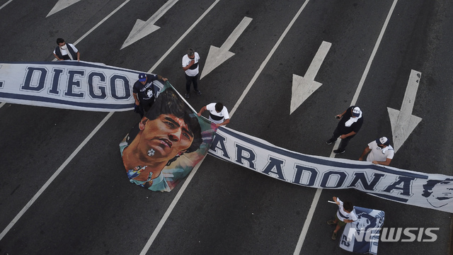 [부에노스아이레스=AP/뉴시스]25일(현지시간) 아르헨티나 부에노스아이레스 시내에서 축구팬들이 디에고 마라도나의 사진과 현수막을 들고 행진하고 있다. 1986년 아르헨티나를 월드컵 우승으로 이끈&nbsp; 아르헨티나 축구 영웅 디에고 마라도나가 25일 부에노스아이레스 자택에서 심장마비로 타계했다. 향년 60세. 2020.11.26. 