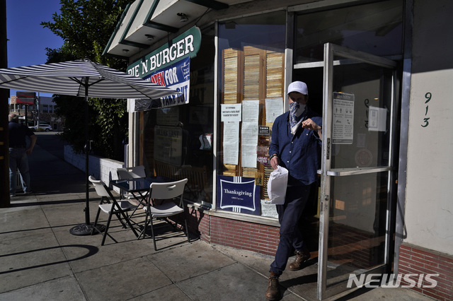 [패서디나=AP/뉴시스]지난 1일 캘리포니아 로스앤젤레스(LA) 동북부 패서디나의 한 식당에서 마스크를 착용한 고객이 문을 열고 나오는 모습. 2020.12.04.