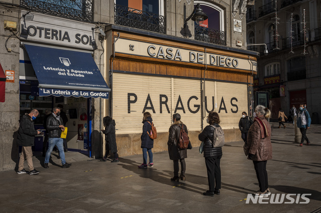[마드리드=AP/뉴시스]지난 3일 스페인 마드리드에서 성탄절 복권을 사려 몰린 시민들이 신종 코로나바이러스 감염증(코로나19) 전파를 막기 위해 마스크를 착용하고 거리 두기를 하는 모습. 2020.12.29.
