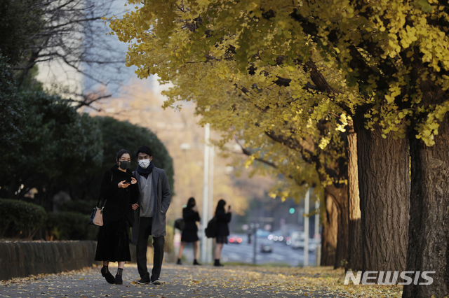 [도쿄=AP/뉴시스]10일(현지시간) 일본 도쿄에서 마스크를 쓴 사람들이 은행나무 밑을 지나고 있다. 2020.12.10.