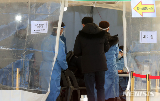 [서울=뉴시스]배훈식 기자 = 신종 코로나바이러스 감염증(코로나19) 확산세가 계속된 15일 오후 서울 서대문구 신촌역 코로나19 임시 선별진료소에서 검사를 받으려는 시민이 문진을 받고 있다. 2020.12.15. dahora83@newsis.com