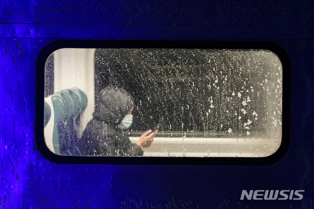 [뉴욕=AP/뉴시스]16일(현지시간) 미국 뉴욕 퀸스 자치구에 눈이 내리기 시작한 가운데 한 승객이 롱아일랜드 레일로드 기차에 타 휴대전화를 바라보고 있다. 2020.12.17.