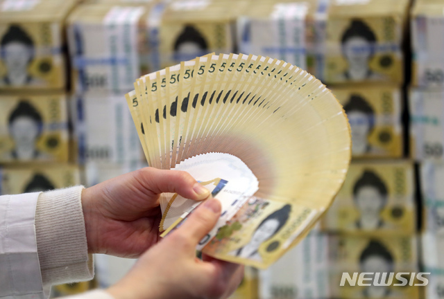 [서울=뉴시스] 고승민 기자 = 한국은행이 미국 연방준비제도이사회(Fed·연준)와의?600억달러 규모의 통화스와프 계약을 6개월 재연장했다고 밝힌 17일 서울 중구 하나은행에서 관계자가 원화를 들어 보이고 있다. 통화스와프는 미리 정한 환율에 따라 필요한 만큼의 돈을 상대국 통화와 교환할 수 있도록 한 계약으로 일종의 '마이너스 통장' 개념이다. 언제든 달러를 꺼내 쓸 수 있다는 점에서 경제·금융위기시 안전판 역할을 한다. 2020.12.17. kkssmm99@newsis.com