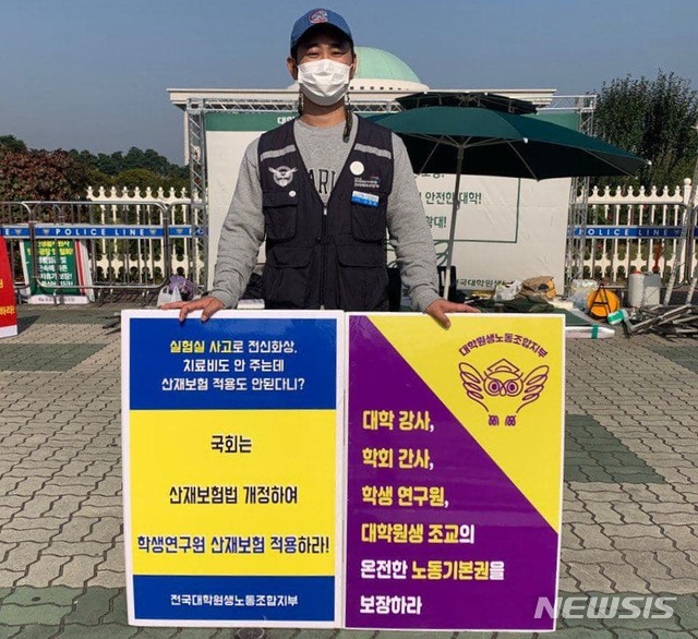 [서울=뉴시스]신정욱 전국공공운수노조 전국대학원생노동조합지부 지부장이 서울 영등포구 국회 앞에서 피켓팅을 하는 모습. 대학원생노조는 21일 오전 국회 앞에서 기자회견을 열고 대학원생들이 빠른 시일 내에 산재보험에 가입할 수 있도록 정치권이 법 개정에 나설 것을 촉구했다. (사진=전국대학원생노조 제공). 2020.12.21.photo@newsis.com