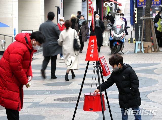 [서울=뉴시스]조수정 기자 = 서울 중구 명동거리에서 한 어린이가  구세군 자선냄비에 용돈을 넣고 있다. 2020.12.31. chocrystal@newsis.com