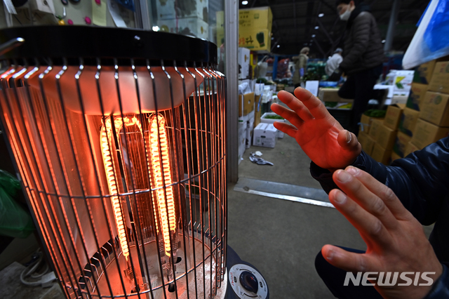 [수원=뉴시스] 김종택기자 = 11일부터 발송되는 전기요금 청구서에는 지금까지 볼 수 없었던 연료비 조정 요금과 기후환경 요금 항목이 새로 추가된다. 사진은 경기도 수원시 권선구 농수산물도매시장에서 한 상인이 전기난로에 손을 녹이는 모습 . 2021.01.05. jtk@newsis.com