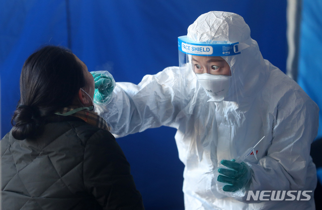 [서울=뉴시스]배훈식 기자 = 6일 오전 서울 영등포구 도림동 배드민턴 체육관에 마련된 신종 코로나바이러스 감염증(코로나19) 임시 선별검사소에서 방호복을 입은 의료진이 검체를 채취하고 있다. 2021.01.06. dahora83@newsis.com