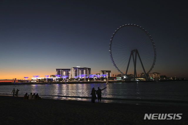 [두바이=AP/뉴시스]12일(현지시간) 아랍에미리트 두바이의 블루워터 아일랜드에서 사람들이 높이 약 260m의 세계 최대 대관람차 '아인 두바이'의 일몰을 감상하고 있다. 대관람차에는 승객이 탈 수 있는 48개의 캡슐 설치가 완료됐으며 각 캡슐에는 약 30명이 탈 수 있는 것으로 알려졌다. 2021.01.13. 