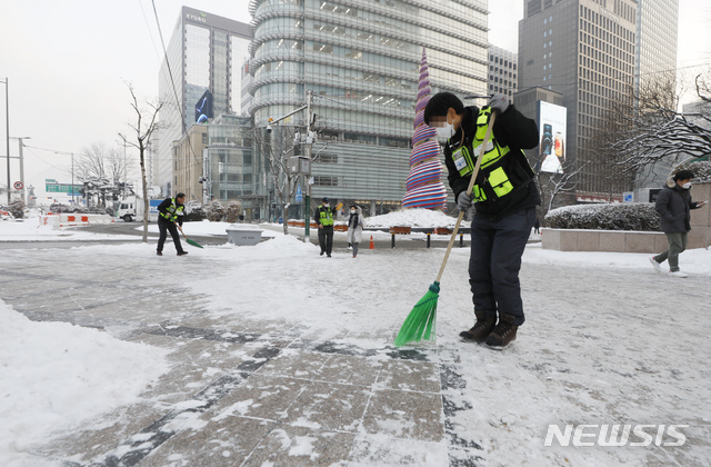 [서울=뉴시스]고승민 기자 = 서울지역에 폭설이 내린 이튿날인 13일 서울 광화문 사거리에서 서울시 관계자들이 제설작업을 하고 있다. 2021.01.13. kkssmm99@newsis.com