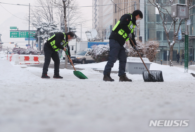 [서울=뉴시스]고승민 기자 = 서울지역에 폭설이 내린 이튿날인 13일 서울 광화문 사거리에서 서울시 관계자들이 제설작업을 하고 있다. 2021.01.13. kkssmm99@newsis.com