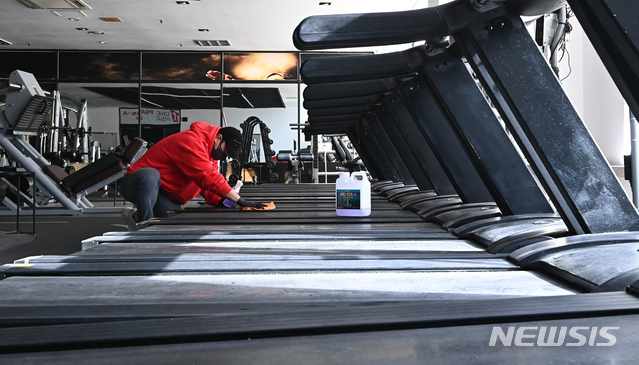 [용인=뉴시스] 김종택기자 = 14일 오후 경기도 용인시 수지구 한 휘트니스센터에서 관계자가 운동기구를 소독하며 영업준비를 하고 있다. 정부는 사회적 거리두기 수도권 2.5단계, 비수도권 2단계 조치 종료를 앞두고 헬스장 등 실내체육시설 집합금지를 완화하되 5인 이상 사적모임 금지 조치는 유지할 가능성이 높다고 밝혔다. 2021.01.14. jtk@newsis.com