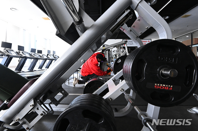 [용인=뉴시스] 김종택기자 = 14일 오후 경기도 용인시 수지구 한 휘트니스센터에서 관계자가 운동기구를 소독하며 영업준비를 하고 있다. 정부는 사회적 거리두기 수도권 2.5단계, 비수도권 2단계 조치 종료를 앞두고 헬스장 등 실내체육시설 집합금지를 완화하되 5인 이상 사적모임 금지 조치는 유지할 가능성이 높다고 밝혔다. 2021.01.14. jtk@newsis.com