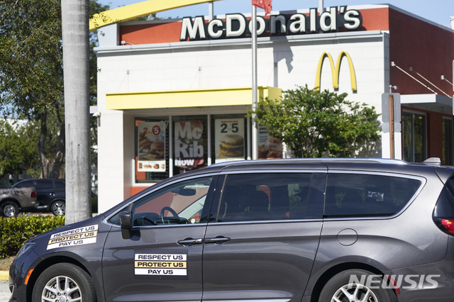 [포트로더데일=AP/뉴시스] 15일(현지시간) 최저시급 15달러를 요구하는 문구를 붙인 차가 미국 플로리다주 포트로더데일에 있는 맥도날드 매장 주변을 돌고 있다. 2021.01.18. 