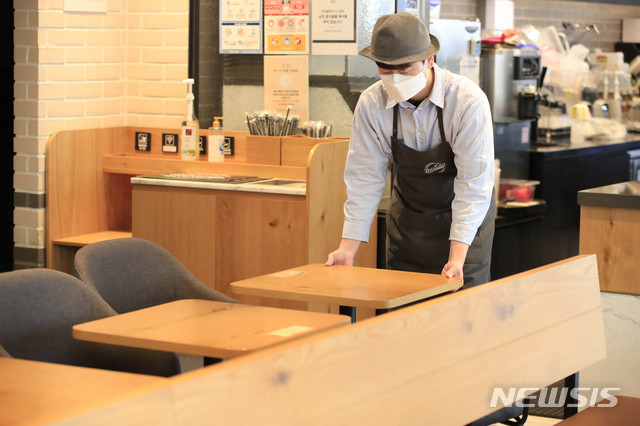 [서울=뉴시스]박민석 기자 = 노래방, 카페 등 일부 다중이용시설과 헬스장 등 실내체육시설에 대한 집합금지·운영제한 완화를 하루 앞둔 17일 오후 서울 마포구의 한 프렌차이즈형 카페에서 직원이 테이블을 정돈하고 있다. 2021.01.17. mspark@newsis.com
