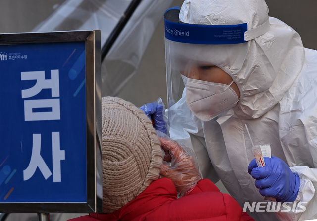 [수원=뉴시스] 김종택기자 = 신종 코로나바이러스 감염증(코로나19) 신규 확진자가 이틀 연속 300명대를 기록한 19일 오후 경기도 수원시 팔달구 수원역에 마련된 코로나19 임시선별검사소에서 의료진이 검체 채취를 하고 있다. 2021.01.19.jtk@newsis.com