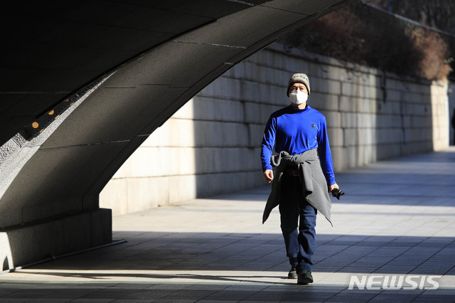 [서울=뉴시스]박민석 기자 = 서울 지역 기온이 영상권을 회복한 지난 20일 오후 서울 청계천에서 한 시민이 외투를 입지 않고 허리에 묶은 채 걷고 있다. 2021.01.20. mspark@newsis.com