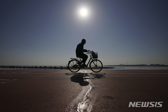 [도쿄=AP/뉴시스]21일 일본 도쿄에서 코로나19 예방을 위해 마스크를 쓴 한 남성이 자전거를 타고 지나가고 있다. 2021.01.21.