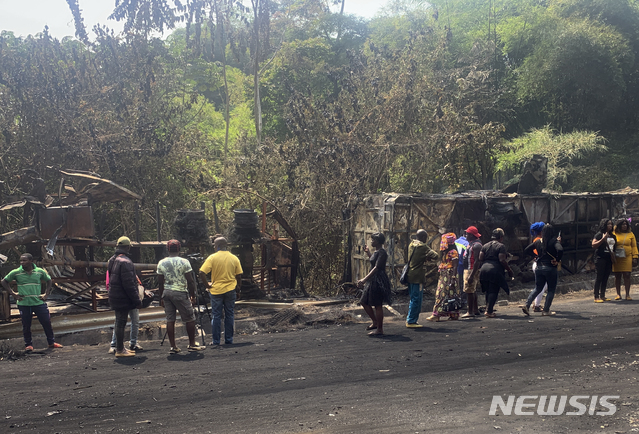 [산추우(카메룬)=AP/뉴시스]카메룬 서부 산추우 마을에서 27일 발생한 버스와 트럭 충돌 화재 사고 현장에 사람들이 모여 있다. 이 사고로 최소 53명이 숨지고 21명이 다쳤다고 관리들이 밝혔다. 2021.1.28