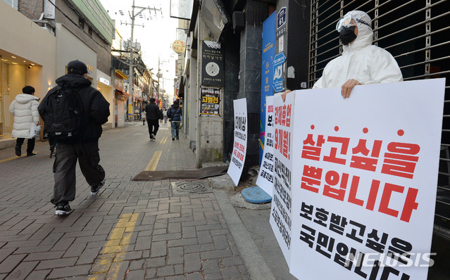 [대구=뉴시스] 이무열 기자 = 3일 오후 대구 중구 동성로의 한 클럽 앞에서 방호복과 고글을 착용한 업주가 신종 코로나바이러스 감염증(코로나19)으로 인한 강제 휴업에 반발하는 피켓시위를 하고 있다. 2021.02.03. lmy@newsis.com