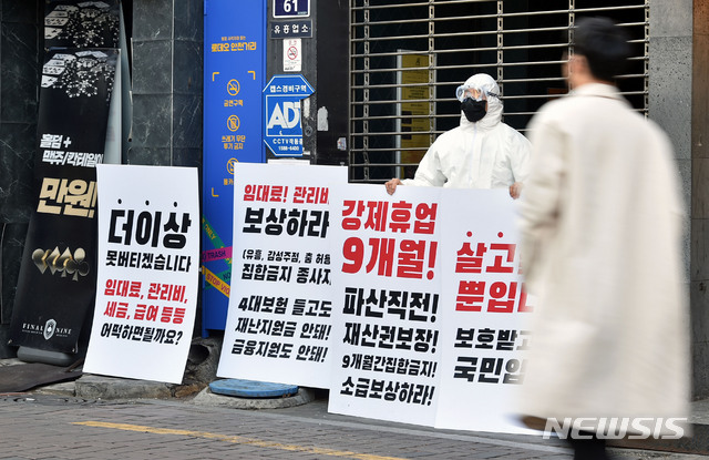 [대구=뉴시스] 이무열 기자 = 3일 오후 대구 중구 동성로의 한 클럽 앞에서 방호복과 고글을 착용한 업주가 신종 코로나바이러스 감염증(코로나19)으로 인한 강제 휴업에 반발하는 피켓시위를 하고 있다. 2021.02.03. lmy@newsis.com