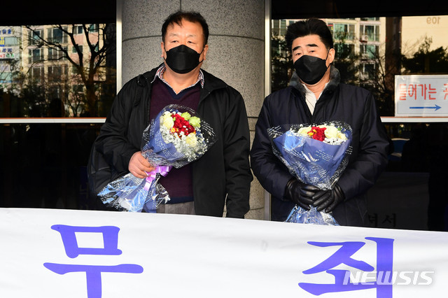 [부산=뉴시스] 부산 '낙동강변 살인사건' 가해자로 몰려 21년간 억울한 옥살이를 한 최인철(왼쪽)씨와 장동익씨가 4일 오전 부산 연제구 부산고등법원에서 열린 재심 선고 공판을 통해 31년 만에 무죄를 선고받은 뒤 꽃다발을 들고 있다. (사진=국제신문 제공). 2021.02.04. photo@newsis.com