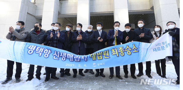 [서울=뉴시스]최진석 기자 = 4일 오전 서울 서초구 대법원에서 열린 평택-당진항 신생 매립지 관련 평택시와 충남 당진시 간 경계분쟁 선고에서 최종 승소를 거둔 정장선(오른쪽 다섯번째) 평택시장을 비롯한 관계자들이 플래카드를 들고 기념촬영하고 있다. 2021.02.04. myjs@newsis.com