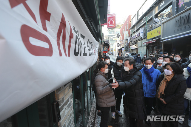 [서울=뉴시스]최동준 기자 = 이낙연 더불어민주당 대표가 4일 오전 서울 용산구 이태원에서 코로나19 피해 맞춤 지원을 위한 현장간담회 장소로 이동하는 도중 피켓을 든 상인들을 위로하고 있다. (공동취재사진) 2021.02.04. photo@newsis.com