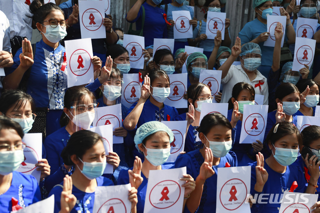 [양곤=AP/뉴시스]5일 미얀마 양곤의 양곤 교육대 캠퍼스 앞에 교사들이 모여 "미얀마 교사들, 시민 불복종"이라고 쓰인 팻말을 들고 세 손가락을 들어 저항의 표시를 하고 있다. 이들은 붉은리본을 달고 학교 앞에 모여 쿠데타 반대 시위를 벌였다. 2021.02.05.