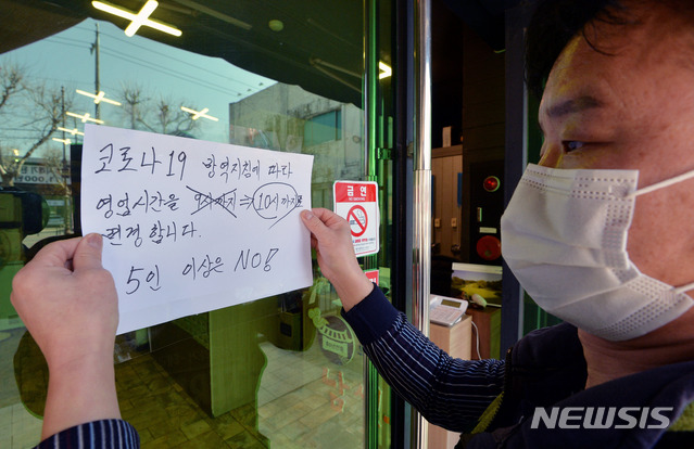 [대구=뉴시스] 이무열 기자 = 8일 오후 대구 수성구 들안길의 한 식당 주인이 변경된 영업시간을 알리는 안내문을 붙이고 있다. 오늘부터 대구를 비롯한 비수도권의 카페와 식당 등 다중이용시설 영업제한이 완화돼 밤 10시까지 이용이 가능해진다. 2021.02.08. lmy@newsis.com