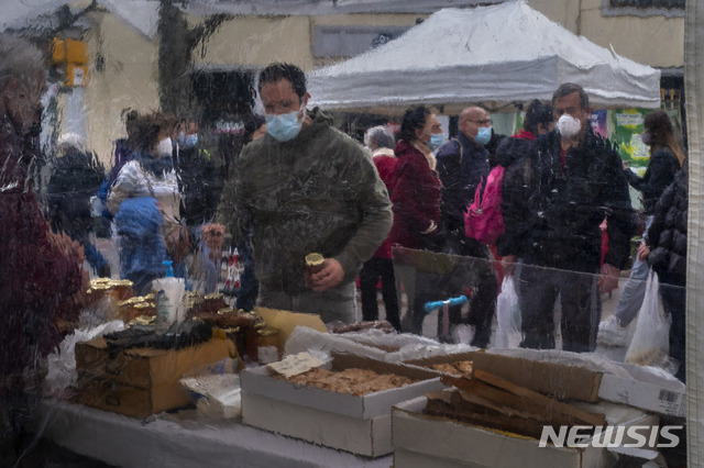 [바르셀로나=AP/뉴시스]9일(현지시간) 스페인 바르셀로나 거리의 한 노점상에 설치된 코로나19 확산 방지용 가림막을 통해 마스크를 쓴 시민들이 거니는 모습이 보인다. 스페인의 코로나19 누적 확진자 수가 300만 명을 넘어서 세계 7번째로 많은 감염자를 기록했으며 사망자는 6만3000명을 넘어섰다. 2021.02.10.