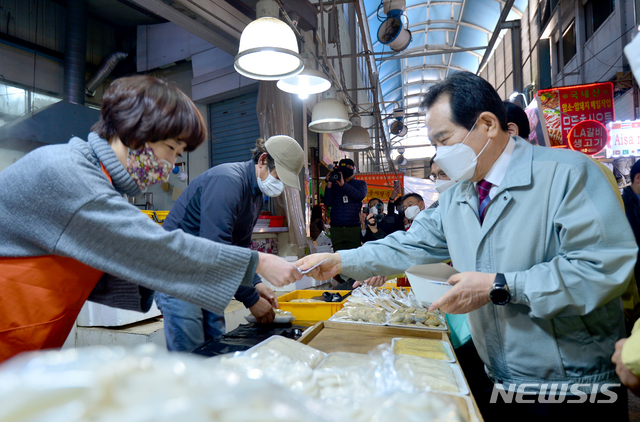 [광주=뉴시스] 김혜인 기자 = 정세균 국무총리가 설 연휴를 하루 앞둔 10일 오후 광주 서구 양동시장을 방문해 떡을 구매하고 있다. 2021.02.10. hyein0342@newsis.com