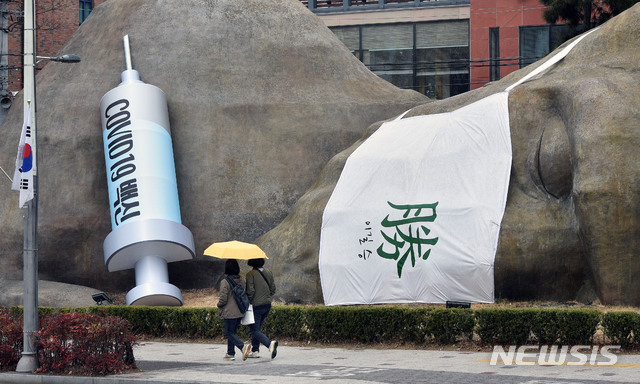 [대구=뉴시스] 이무열 기자 = 신종 코로나바이러스 감염증(코로나19) 백신 국내 접종 시작을 하루 앞둔 25일 오후 대구 달서구 진천동 선사유적공원 입구 원시인 조형물에 대형 주사기가 설치돼 눈길을 끌고 있다. 2021.02.25. lmy@newsis.com