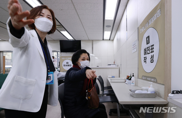 [서울=뉴시스]사진공동취재단 = 26일 오전 서울 금천구 보건소에서 노인요양센터 요양보호사 신정숙 씨가 신종 코로나바이러스 감염증(코로나19) 아스트라제네카(AZ) 백신 1회차 접종에 앞서 보건소 직원의 안내를 받고 있다. 2021.02.26. photo@newsis.com