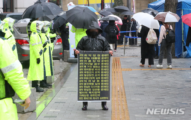 [서울=뉴시스]배훈식 기자 = 제102주년 3.1절인 1일 오후 서울 중구 한국전력공사 서울본부 앞에서 열린 '국민 대각성 자유민주주의 체제 수호 국민총궐기 3.1절 국민대회'에 참석한 보수단체 회원이 문재인 대통령을 비난하는 피켓을 들고 있다. 2021.03.01. dahora83@newsis.com