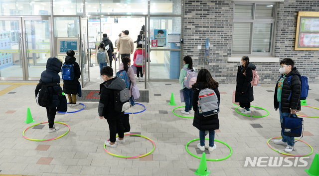 [전주=뉴시스] 김얼 기자 = 전국적으로 초등학교 개학을 맞이한 2일 전북 전주시 전주효천초등학교에서 학생들이 훌라후프로 만들어놓은 거리두기 표시를 지키며 교실에 들어서고 있다. 2021.03.02. pmkeul@newsis.com
