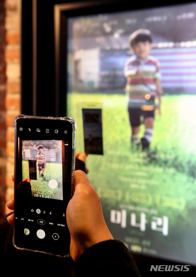 [서울=뉴시스]김병문 기자 = 영화 '미나리' 개봉날인 3일 오후 서울 한 영화관에서 영화를 본 시민이 포스터를 찍고 있다. 2021.03.03. dadazon@newsis.com