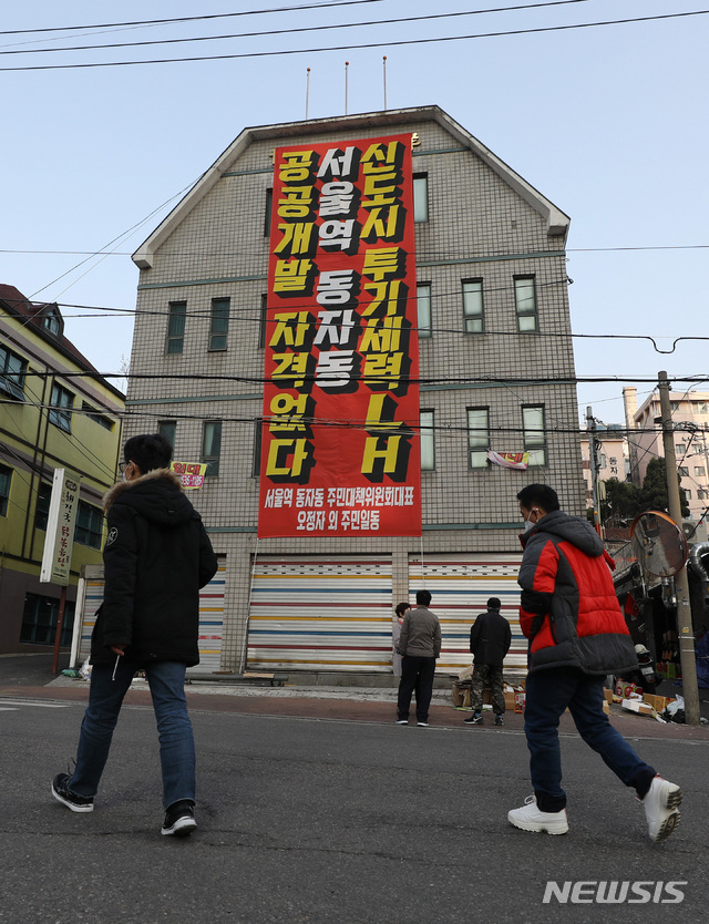 [서울=뉴시스]이영환 기자 = 한국토지주택공사(LH) 임직원의 광명·시흥 신도시 투기 의혹 논란이 지속되고 있는 지난 8일 오후 서울 용산구 동자동 일대 건물 외벽에 공공주택 토지 강제수용 반대 현수막이 걸려있다. 정부는 지난달 5일  동자동 일대 쪽방촌 4만7000㎡를 2410가구가 들어서는 공공주택 단지로 조성한다는 계획을 발표했다. 2021.03.08. 20hwan@newsis.com