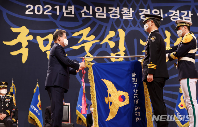 [아산=뉴시스]추상철 기자 = 문재인 대통령이 12일 오후 충남 아산시 경찰대학에서 열린 신임 경찰 경위·경감 임용식에 참석해 국가수사본부 기에 수치를 수여하고 있다. 2021.03.12. scchoo@newsis.com