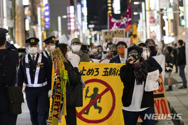 [도쿄=AP/뉴시스]25일 일본 도쿄에서 2020 도쿄올림픽·패럴림픽 강행에 반대하는 시위대가 성화봉송 반대 현수막을 들고 긴자 거리를 행진하고 있다. 2021.03.26.