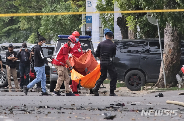 [마카사르=AP/뉴시스]28일(현지시간) 인도네시아 술라웨시 남부 마카사르의 한 성당 밖에서 폭발이 일어나 경찰과 구조대가 시신이 담긴 것으로 보이는 가방을 옮기고 있다. 경찰은 자살폭탄테러로 보이는 이 폭발로 용의자 1명이 숨지고 10명이 다쳤다고 밝혔다. 2021.03.28.