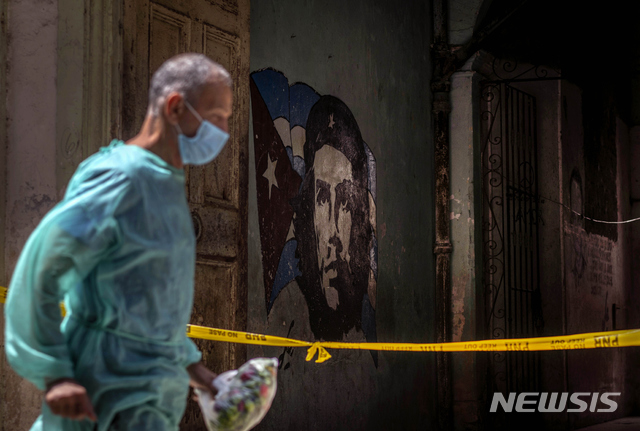 [아바나=AP/뉴시스]7일(현지시간) 쿠바 수도 아바나에서 마스크를 쓴 한 의료 종사자가 코로나19로 격리된 한 가정집 앞을 지나고 있다. 쿠바의 코로나19 누적 확진자 수는 8만1640명, 사망자는 440명으로 집계됐다. 2021.04.08.