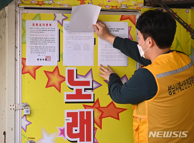 [성남=뉴시스] 김종택기자 = 수도권 지역 유흥시설의 영업이 금지된 13일 오후 경기도 성남시 중원구 한 노래방 출입구에서 성남시청 공무원들이 집합금지 명령서를 붙이고 있다. 성남시는 노래방과 관련한 코로나19 확진자가 집단 발생함에 따라 다음달 2일까지 지역 내 모든 노래방에 대해 집합금지 행정명령을 내렸다. 2021.04.13. jtk@newsis.com