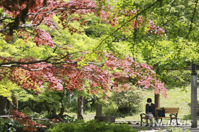 [도쿄=AP/뉴시스]19일 일본 도쿄의 한 공원에서 코로나19 확산을 막기 위해 마스크를 쓴 한 여성이 의자에 앉아 쉬고 있다. 고이케 유리코 도쿄도지사와 요시무라 히로후미 오사카부 지사는 "코로나19의 심각한 상황이 계속되고 있다”라며 대책 회의를 통해 긴급사태 선언 발령을 국가에 요청할 것을 시사했다. 2021.04.19.