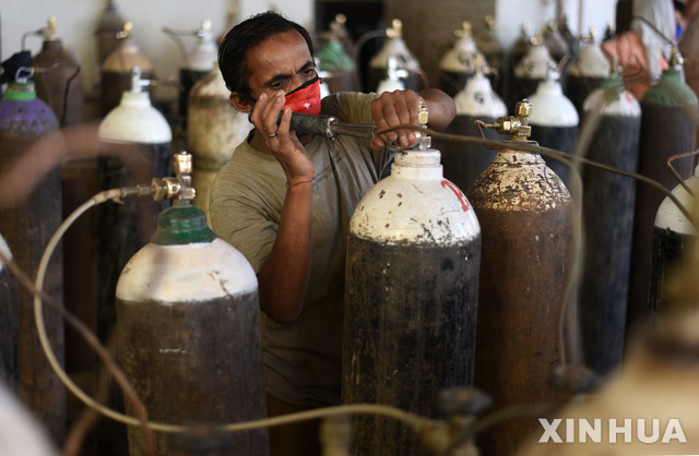 [프라야그라지=신화/뉴시스]4월19일(현지시간) 인도 프라야그라지의 한 코로나19 병원에서 근로자들이 의료용 산소 탱크를 채우고 있다. 인도의 코로나19 누적 확진자 수가 1531만4714명을 기록했으며 사흘 연속 일일 확진자 수 25만 명을 넘어섰다. 2021.04.20.