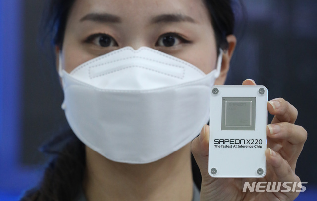 [서울=뉴시스]조수정 기자 = 21일 오전 서울 삼성동 코엑스에서 열린 '월드IT쇼 2021'에서 SKT 부스 직원이 AI 반도체를 들어보이고 있다. 2021.04.21. chocrystal@newsis.com