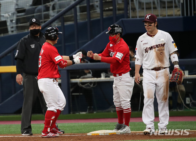 [서울=뉴시스]고범준 기자 = 23일 오후 서울 구로구 고척스카이돔에서 열린 2021 KBO리그 키움 히어로즈와 SSG 랜더스 경기, 3회초 2사 2,3루 SSG 최주환이 2타점 안타를 치고 코치와 하이파이브 하고 있다. 2021.04.23. bjko@newsis.com