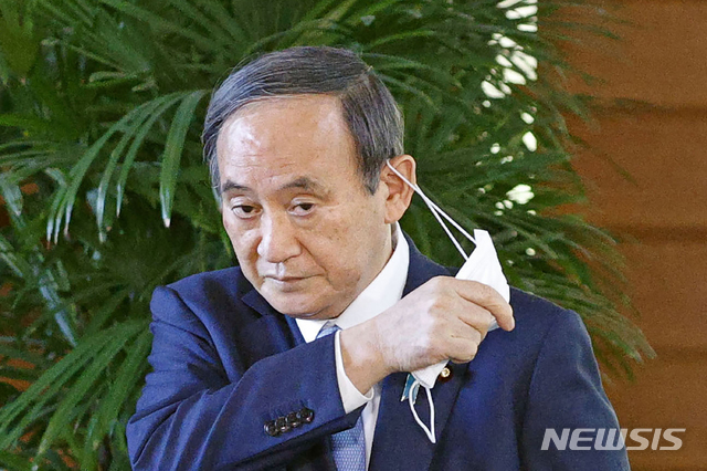[도쿄=AP/뉴시스]지난 26일 스가 요시히데 일본 총리가 도쿄 총리 관저 앞에서 기자들에게 발언하기 전 마스크를 벗고 있다. 2021.04.27.
