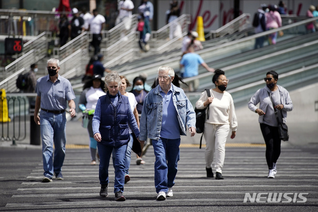 [라스베이거스=AP/뉴시스]27일(현지시간) 미 네바다주 라스베이거스에서 마스크를 쓰거나 쓰지 않은 보행자들이 거리를 걷고 있다. 미국 질병통제예방센터(CDC)는 코로나19 백신 접종을 완료한 경우 야외에서 마스크를 쓰지 않아도 된다고 발표하며 야외 마스크 착용에 대한 지침을 완화했다. 2021.04.29. 